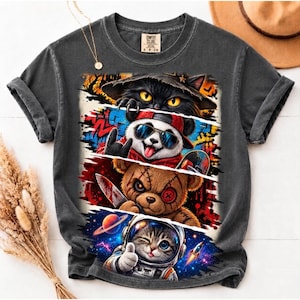Peut inclure: Un t-shirt gris anthracite à manches courtes avec une impression graphique divisée en quatre panneaux horizontaux. Le motif montre un chat noir avec un chapeau, un panda avec des lunettes de soleil, un ours en peluche cousu avec un couteau et un chaton en combinaison spatiale.