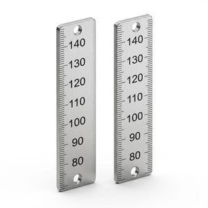 Può includere: Due strisce metalliche rettangolari color argento con scale di misurazione verticali. Ogni striscia mostra numeri neri stampati da 80 a 140 con tacche corrispondenti e un foro circolare sia all'estremità superiore che a quella inferiore.