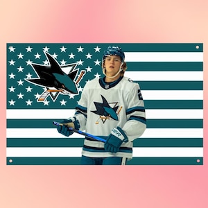 Könnte beinhalten: Ein rechteckiges Wandbanner mit einem Eishockeyspieler in einem weißen Trikot mit einem blaugrünen und schwarzen Haifisch-Logo. Der Hintergrund ist eine stilisierte Flagge mit blaugrünen und weißen horizontalen Streifen und weißen Sternen.