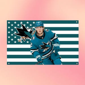 May include: A rectangular metal sign featuring a hockey player in a teal and white uniform with a shark logo. The background displays a stylised flag pattern with teal and white horizontal stripes and a field of white stars on a teal background.