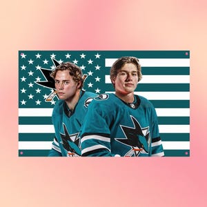 Könnte beinhalten: Ein rechteckiges Wandschild mit zwei Eishockeyspielern in türkisfarbenen Trikots mit dem Logo der San Jose Sharks. Der Hintergrund zeigt ein stilisiertes amerikanisches Flaggenmuster mit türkisfarbenen Streifen und weißen Sternen.