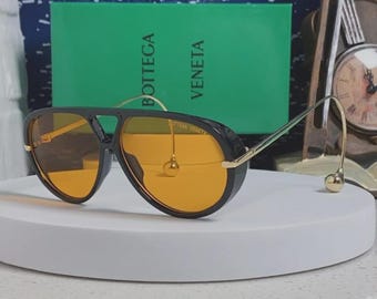 Gafas de sol Bottega Veneta BV1273S con montura negra y lentes naranjas, 63-12-175