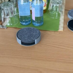 Runder Untersetzerhalter in Grau mit Filzuntersetzern in Stone Grey auf einem gedeckten Tisch mit Gläsern und Flaschen (Untersetzer nicht im Lieferumfang)