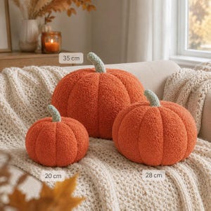 May include: Three orange pumpkin-shaped pillows with textured, fuzzy fabric and light green stems. The pillows are labeled with sizes of 20 cm, 28 cm, and 35 cm. These round, plush decorative items feature deep vertical ridges and a soft, boucl&eacute;-like surface.