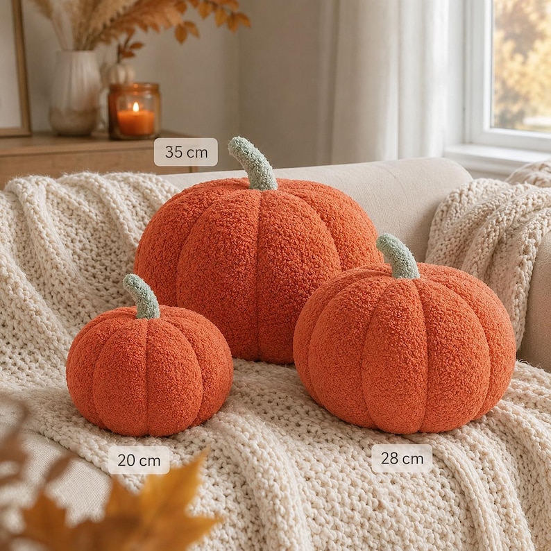 May include: Three orange pumpkin-shaped pillows with textured, fuzzy fabric and light green stems. The pillows are labeled with sizes of 20 cm, 28 cm, and 35 cm. These round, plush decorative items feature deep vertical ridges and a soft, boucl&eacute;-like surface.
