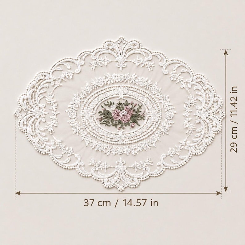 May include: An oval white lace doily featuring intricate floral embroidery in the center with pink and green thread. The lace border has a detailed scalloped edge. Dimensions are 14.57 inches in width and 11.42 inches in height as indicated.