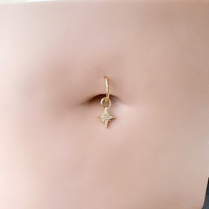Può includere: Anello per ombelico dorato con un piccolo ciondolo a stella scintillante.