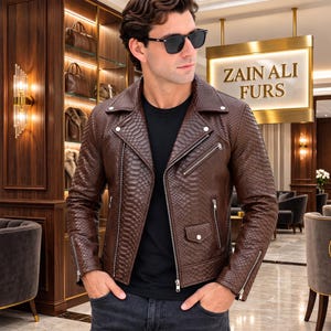 Peut inclure: Une veste de motard en cuir marron avec un motif texturé en peau de serpent, dotée de fermetures éclair en métal argenté sur le devant, la poitrine et les poignets, d'un revers cranté et d'une petite poche à rabat avec bouton-pression argenté.