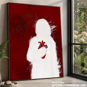 Op de afbeelding: Een ingelijste muurkunstprint met een wit, abstract silhouet van een persoon tegen een dieprode achtergrond. De figuur houdt een gedetailleerd, realistisch anatomisch hart in rode en blauwe tinten in het midden van de borstkas.