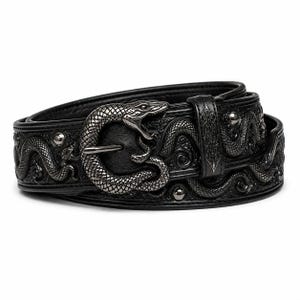 Könnte beinhalten: Ein schwarzer Ledergürtel mit einer metallischen Schnalle in Form einer gewundenen Schlange mit offenem Maul. Der Gürtelriemen ist mit einem durchgehenden Schlangenmuster geprägt und mit kleinen, runden, dunkelmetallischen Nieten verziert.