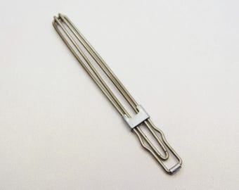 May include: A silver-colored metal hair clip with a unique design. The clip features three parallel wires held together by a rectangular clasp and a curved handle. The clip is designed to hold hair in place.