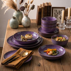 May include: A set of purple ceramic dinnerware featuring plates and bowls with a speckled finish and dark rims. The collection includes stacked bowls, flat plates, and individual bowls containing food, accompanied by a gold fork and spoon on a napkin.