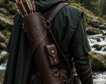 May include: A dark brown leather quiver worn on the back, featuring a stamped leaf design, brass hardware, and an attached small pouch. The quiver contains several wooden arrows with feathered fletching and is secured with adjustable leather straps.