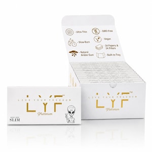 Puede incluir: Una caja blanca de papel de fumar LYF Platinum King Size Slim con texto dorado y un gráfico alienígena. La tapa abierta muestra iconos de ultra fino, sin OGM, vegano, combustión lenta, 34 papeles y filtros, goma arábiga natural y bandeja integrada.