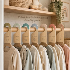 May include: A set of seven wooden clothing dividers hanging on a rod, each featuring a different colored top and a unique animal illustration. The text reads: Perfect sizes. Perfectly organized. Loved by parents. The dividers are labeled by age from newborn to 18-24 months, organizing various baby garments.