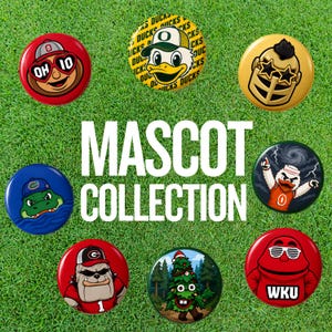 May include: A collection of seven circular pin-back buttons featuring various colorful cartoon mascots, including a bulldog, a duck, a tree, and a knight, arranged around the white text MASCOT COLLECTION on a green grass-textured background.