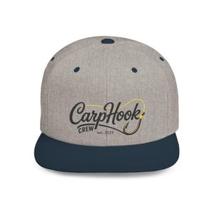 Könnte beinhalten: Eine baseballkappe in grau meliert mit einem dunkel marineblauen schirm und oberem knopf. Die vorderseite zeigt den gestickten schriftzug CarpHook CREW est. 2026 in schwarz, mit einer gelben angelhaken-grafik im schriftzug integriert.