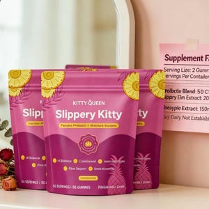 May include: Three pink pouches of Kitty Queen Slippery Kitty gummies featuring pineapple illustrations and text. A pink note displays Supplement Facts, including Serving Size: 2 Gummies, Servings Per Container: 30, Probiotic Blend: 50 CFU, Slippery Elm Extract: 200mg, and Pineapple Extract: 150mg.
