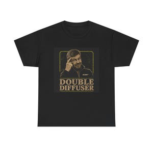 Puede incluir: Una camiseta negra de manga corta con un estampado gráfico de una persona señalando su sien. El diseño incluye un marco cuadrado con borde amarillo y el texto "DOUBLE DIFFUSER" en una fuente beige, negrita y desgastada debajo.