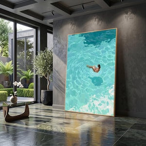 May include: A large vertical rectangular wall art print featuring a painting of a person floating in clear turquoise water on a white circular pool float while reading a book, framed in a thin light wood frame and displayed against a dark wall.