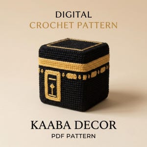 May include: A digital crochet pattern for a cube-shaped Kaaba decor. The crocheted object is black with gold-colored yarn detailing, featuring a rectangular emblem on the front. The text reads DIGITAL CROCHET PATTERN and KAABA DECOR PDF PATTERN.
