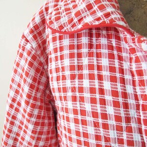 May include: Red and white checkered quilted robe with a red trim around the collar.