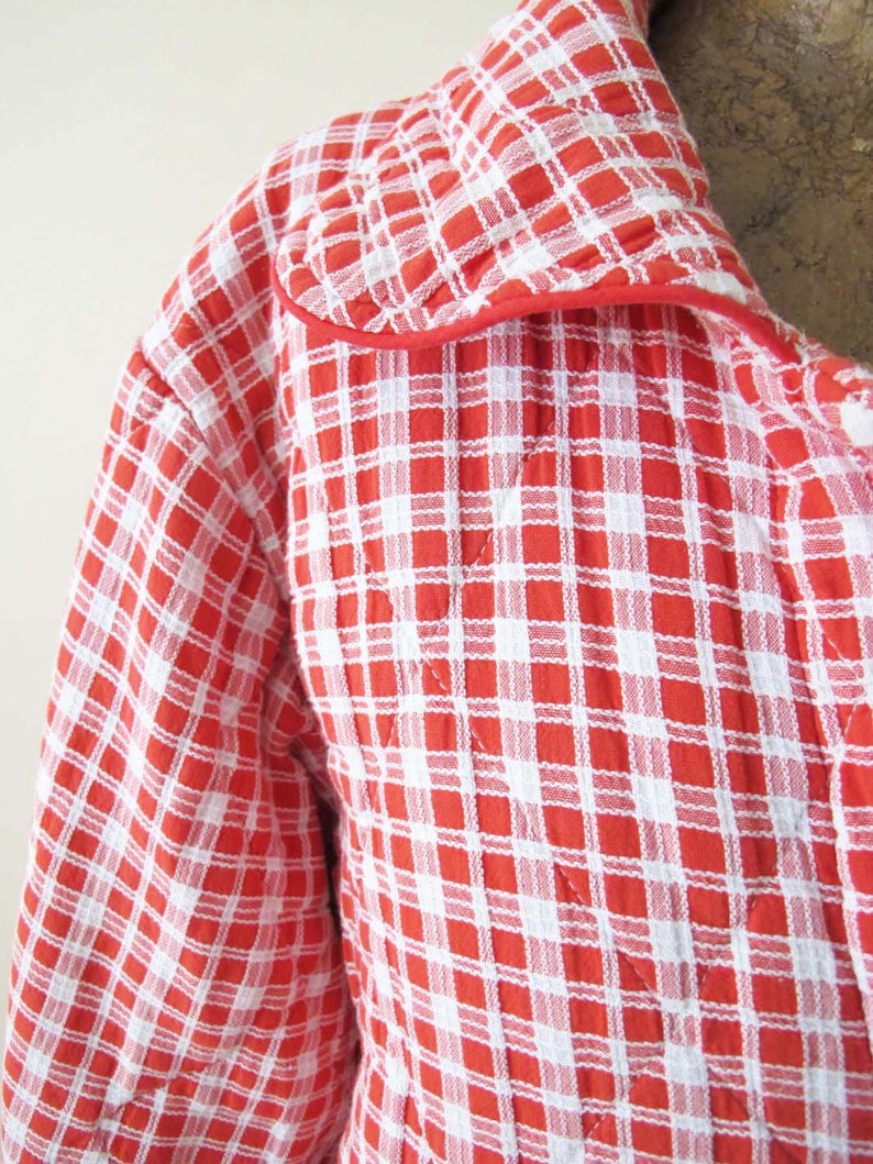 May include: Red and white checkered quilted robe with a red trim around the collar.