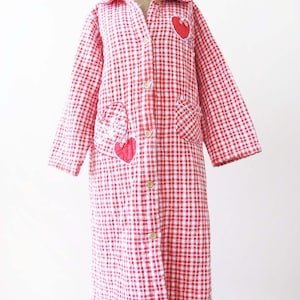 May include: A red and white gingham robe with a long sleeve and button closure. The robe has two heart-shaped patches on the front.