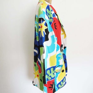 May include: A long-sleeved, multi-colored blazer with a geometric and floral print. The blazer is made of a lightweight fabric and has a relaxed fit.