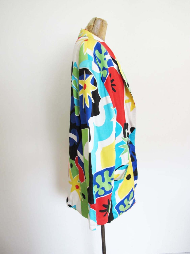 May include: A long-sleeved, multi-colored blazer with a geometric and floral print. The blazer is made of a lightweight fabric and has a relaxed fit.