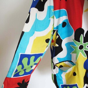 May include: A colorful, abstract patterned jacket with a long sleeve. The jacket is made of a lightweight fabric and features a variety of colors, including red, blue, yellow, green, and black.