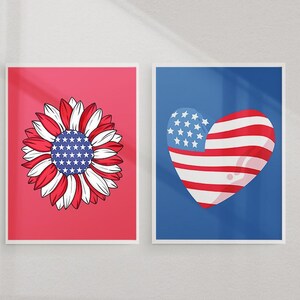 Pu&ograve; includere: Due stampe incorniciate con temi patriottici. Una presenta un girasole con petali rossi, bianchi e blu e un centro pieno di stelle. L'altra stampa raffigura un cuore con strisce rosse e bianche e una sezione blu con stelle.