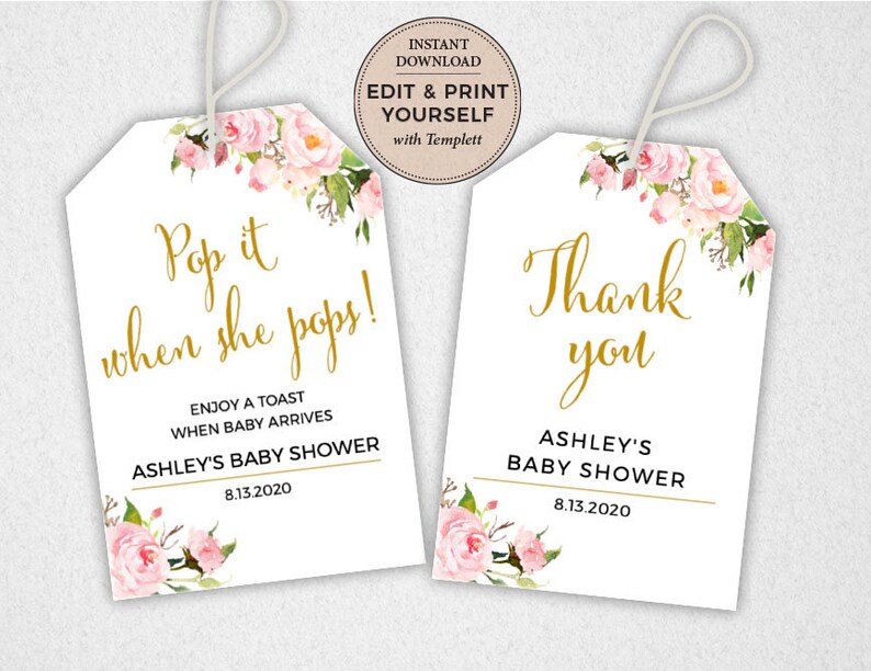 May include: Two white gift tags with pink floral designs and gold lettering. The first tag says "Pop it when she pops!" and "Enjoy a toast when baby arrives Ashley's Baby Shower 8.13.2020". The second tag says "Thank you Ashley's Baby Shower 8.13.2020".