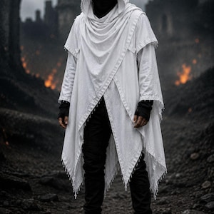May include: A white hooded cloak with a draped, layered front and fringed edges, worn over a black long-sleeved shirt, black trousers, and black boots. The cloak features a textured fabric and a deep hood that covers the head, paired with black fingerless gloves and a black face covering.