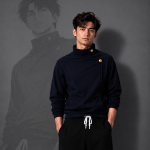 以下が含まれることがあります： ハイカラーで左側に2つの金色のボタンが付いたダークネイビーの長袖プルオーバー。ウエストに白いドローストリングが付いた黒いパンツと組み合わされています。同じ服装のイラストグラフィックが背景に表示されています。