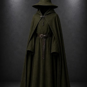 May include: A dark olive green hooded cloak and matching pointed hat ensemble. The cloak features a front toggle closure at the neck and a long, flowing floor-length skirt. A dark brown leather belt with a metal buckle is cinched at the waist.