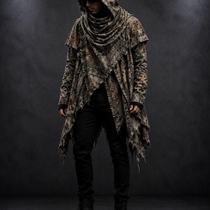 Peut inclure: Une veste à capuche à manches longues avec un motif camouflage marron, vert et beige, dotée d'un col bénitier drapé, d'un ourlet asymétrique aux bords effilochés, portée avec un pantalon noir et des bottines à lacets en cuir noir.