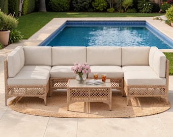 May include: A U-shaped outdoor sectional sofa with light beige cushions and a light brown woven wicker base featuring a lattice pattern. A matching square coffee table with a glass top sits in the center, holding a glass vase of pink flowers.