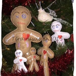 May include: A collection of handmade felt voodoo doll ornaments in various sizes. The dolls are tan and white with embroidered details, including hearts and skeletal designs. They are displayed on a Christmas tree with red tinsel and a decorative bird.