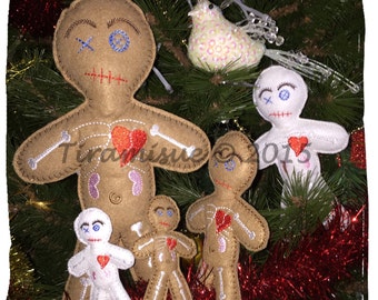 May include: A collection of handmade felt voodoo doll ornaments in various sizes. The dolls are tan and white with embroidered details, including hearts and skeletal designs. They are displayed on a Christmas tree with red tinsel and a decorative bird.