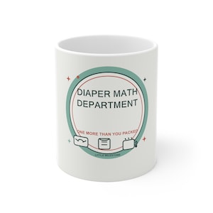 May include: A white ceramic mug featuring a circular graphic with the text DIAPER MATH DEPARTMENT and ONE MORE THAN YOU PACKED. The design includes small icons of a scale, a diaper, and a mug, accented by teal and red colors and stars.