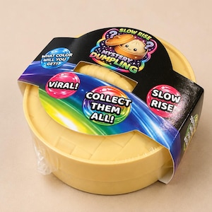 May include: A yellow round container with a textured lid resembling a bamboo steamer, wrapped in a black cardboard sleeve featuring the text Mystery Dumpling, Slow Rise, Viral, What Color Will You Get, and Collect Them All with rainbow graphics.