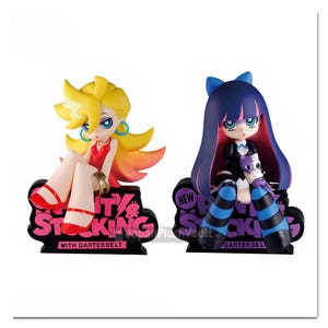 以下が含まれることがあります： 大きな目をしたアニメスタイルのフィギュア2体。左のフィギュアは黄色い髪に赤いドレスと赤い靴を着用。右のフィギュアは青い髪に黒いドレスと縞模様のストッキングを着用。両方ともPanty & Stockingと書かれた黒い台座の上に座っている。