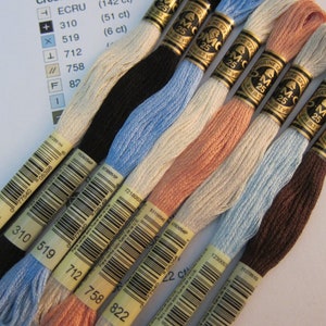 May include: Eight spools of DMC embroidery floss in various colours, including ecru, black, light blue, peach, white, and brown. Each spool has a yellow label with a barcode and the DMC number printed on it.