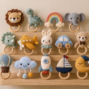 May include: A collection of fourteen crochet baby rattles, each featuring a unique stuffed shape attached to a smooth wooden ring. The designs include a lion, dinosaur, rainbow, elephant, triceratops, airplane, bunny, car, bear, hot air balloon, cloud, rocket, sailboat, and moon.