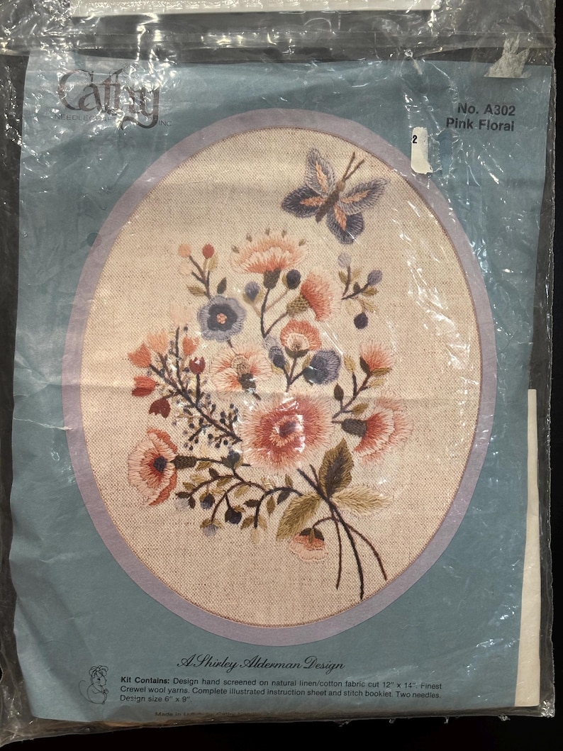 Op de afbeelding: Een borduurpakket getiteld Pink Floral, nr. A302, met een ontwerp van Shirley Alderman. Het pakket bevat een natuurlijke linnen/katoenen stof met een handbedrukt bloemen- en vlinderpatroon, wolgaren, twee naalden en een instructieblad.