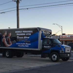 Pode incluir: Um caminhão azul e preto com o texto Mobile Personal Training Gym, Resultz, All About Results, www.resultz.fitness e 732.492.7442. A lateral exibe um gráfico de duas pessoas se exercitando com pesos contra um fundo escuro.