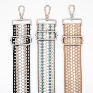 May include: Three decorative bag straps with silver-tone metal hardware. The straps feature woven patterns in black, beige, and white; blue, beige, and white; and beige and white. Each strap has a metal clasp at the top and a metal buckle.