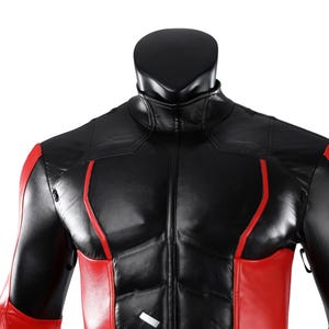 Pu&ograve; includere: Una giacca nera e rossa con colletto alto e chiusura frontale a zip. Il capo presenta un design strutturato con pannelli neri sul petto e sulle spalle, accentuati da vivaci strisce verticali rosse lungo i lati e le maniche.