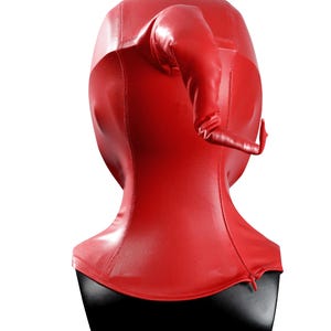 Pu&ograve; includere: Un cappuccio rosso brillante che copre l'intera testa, realizzato in un materiale liscio simile alla pelle. Il cappuccio presenta una prominente protuberanza curva a forma di corno sulla parte superiore e una cerniera alla base del collo a destra.